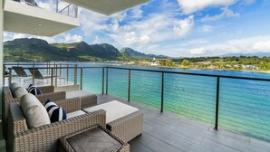 A balcony with wicker furniture and a view of a lake and mountains. - Modern Oceanfront Resort Living. Luxury Oceanfront Bedroom Suites. Sleeps 10! (Lihue)