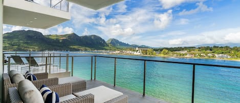Ein Balkon mit Korbmöbeln und Blick auf einen See und Berge.