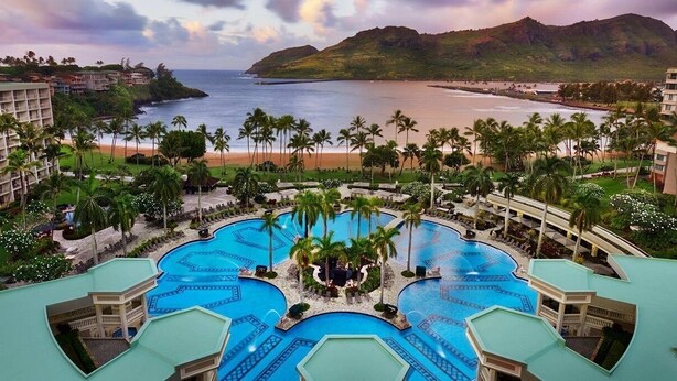 A resort with multiple swimming pools, palm trees, and a view of the ocean. - Modern Oceanfront Resort Living. Luxury Oceanfront Bedroom Suites. Sleeps 10! (Lihue)
