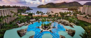 Ein Resort mit mehreren Schwimmbecken, Palmen und Blick auf den Ozean.