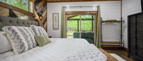 Un dormitorio con una cama grande, techo de madera y vistas al exterior a través de una ventana.