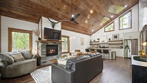 A spacious living room with a fireplace, a large sofa, and a television. - Couple's Escape + King Bed + Fountain + Hot Tub (Broken Bow)
