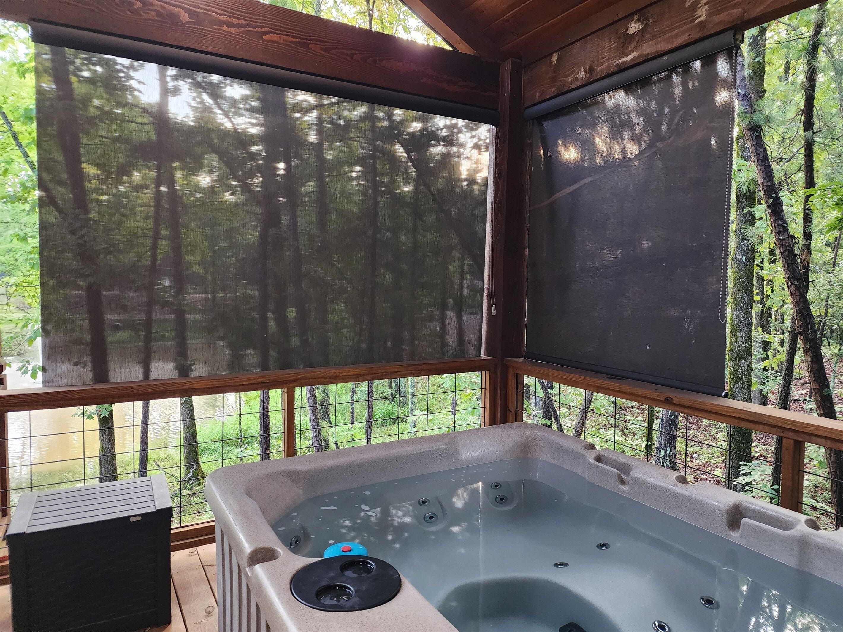 A hot tub in a covered outdoor area with a view of a forest.