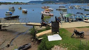 A marina with boats docked, a wooden dock, and a grassy area with a motorcycle. - Paraty house near historic center (paraty)
