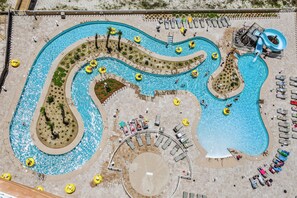 An aerial view of a resort with multiple swimming pools, sun loungers, and a water slide.