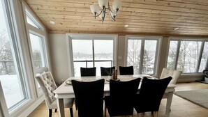 A dining area with a wooden ceiling, large windows, and a chandelier. - 5-Bedroom Executive Lakefront Retreat Sleeping 12- Relax, Recharge and Reconnect (Greater Sudbury)