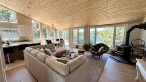 A spacious living area with a large L-shaped sofa, a dining table with chairs, and a fireplace. - 5-Bedroom Executive Lakefront Retreat Sleeping 12- Relax, Recharge and Reconnect (Greater Sudbury)
