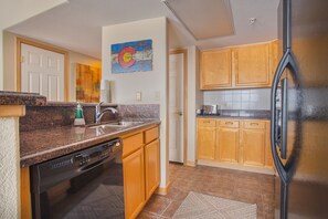 Kitchen features a dishwasher, sink, refrigerator, and a painting above the sink.