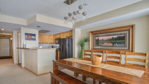 Una cocina amplia con armarios de madera, una isla central y un comedor con mesa y banco de madera.