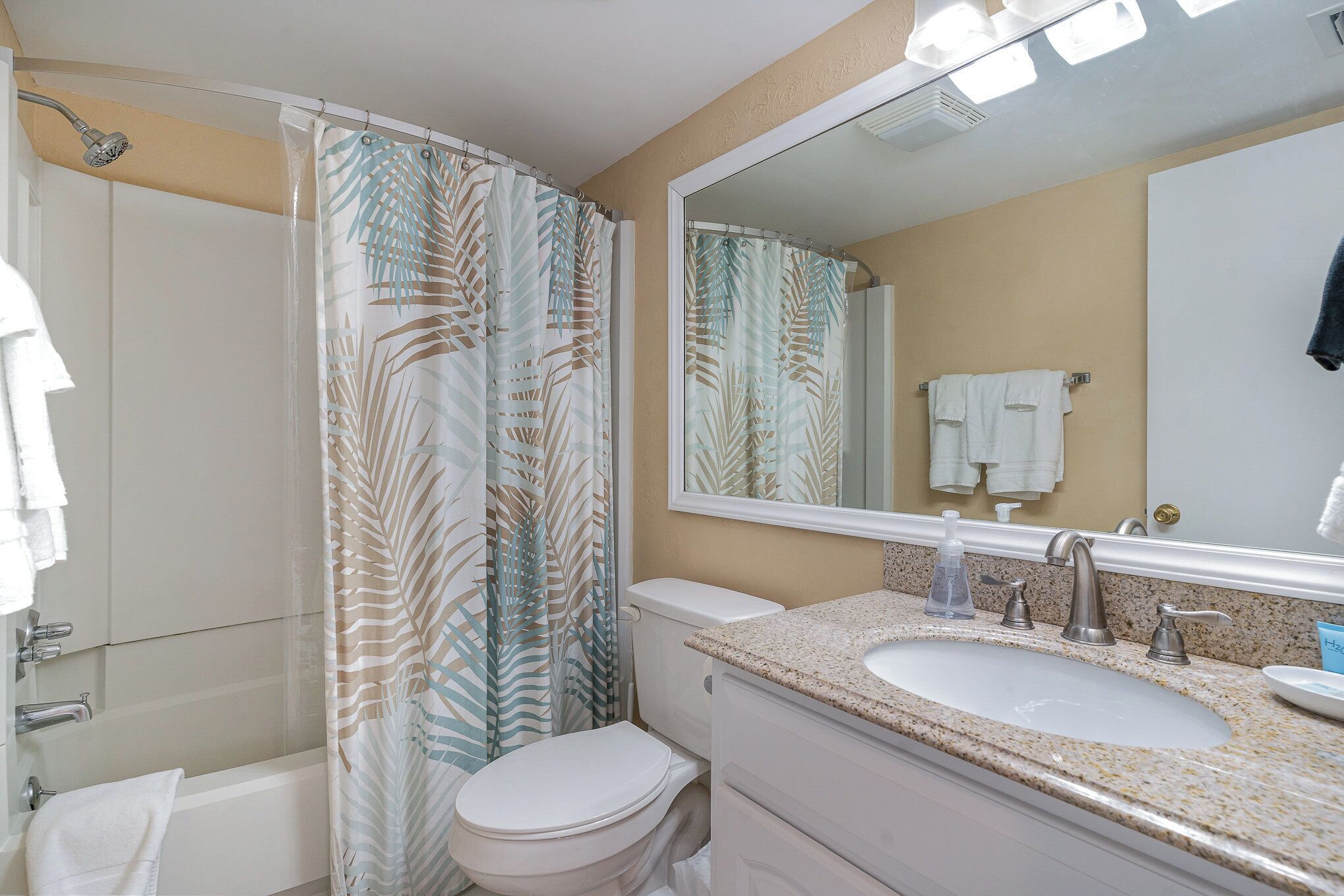 A bathroom with a shower, toilet, sink, and a mirror.