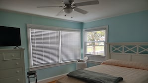 Un dormitorio con cama, cómoda y ventilador de techo.