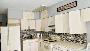 A compact kitchen with white cabinets, a stove, and a built-in oven.