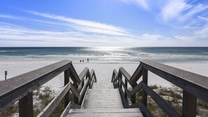 Une promenade en bois menant à une plage, avec un ciel dégagé.