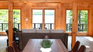Un coin repas en bois avec une longue table, des bancs et une plante en pot.