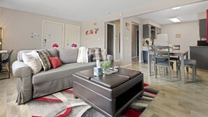 Un salon moderne avec un canapé gris, une table basse et un coin repas comprenant une table et des chaises.