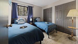 Une chambre avec deux lits, une fenêtre avec des rideaux, une lampe et une armoire.