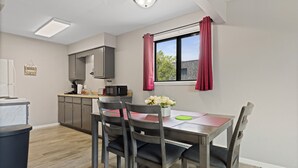 Une cuisine compacte avec des meubles gris, un four à micro-ondes et une petite table à manger avec des chaises.