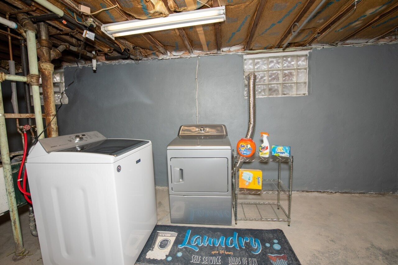 A laundry room with a washing machine, dryer, and a shelf with cleaning supplies.