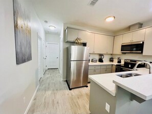 Enjoy cooking in this well-equipped kitchen with a stainless steel refrigerator, oven, microwave, and sink.