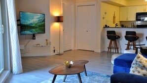 Een moderne woonkamer met een flatscreen televisie, een salontafel en een blauwe bank.
