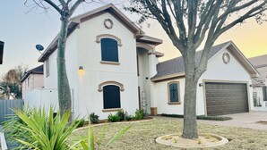 A two-story house with a garage, surrounded by a well-maintained lawn and a variety of plants. - 🏡 Home sweet Home in the ❤️of McAllen (McAllen)