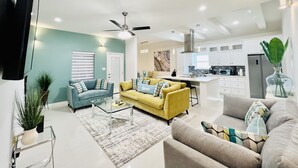 A modern living room with a sofa, coffee table, and a dining area with a kitchen in the background. - 🏡 Home sweet Home in the ❤️of McAllen (McAllen)