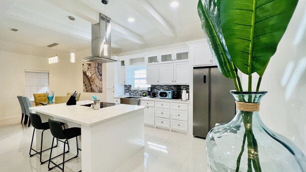 A modern kitchen with white cabinets, stainless steel appliances, and a central island with bar stools. - 🏡 Home sweet Home in the ❤️of McAllen (McAllen)