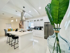 A modern kitchen with white cabinets, stainless steel appliances, and a central island with bar stools. - 🏡 Home sweet Home in the ❤️of McAllen (McAllen)