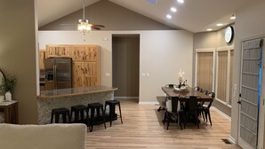 Une cuisine moderne avec des meubles en bois, un réfrigérateur en acier inoxydable et un coin bar avec des tabourets.