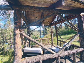 Una estructura de madera rústica con techo inclinado, vigas de madera y vistas a un paisaje natural.