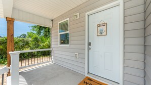 A porch with a white door, a welcome mat, and a small window. - Stylish 2 bedroom home close 2 Dtown, NAS, and BCH (Pensacola)