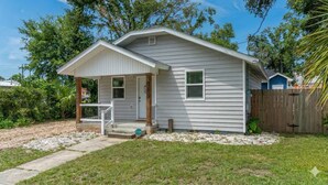 A single-story house with a front porch, a small garage, and a wooden fence. - Stylish 2 bedroom home close 2 Dtown, NAS, and BCH (Pensacola)