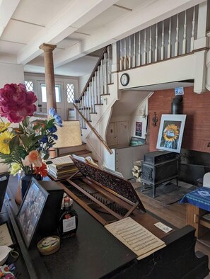 A lobby with a staircase, a fireplace, and a desk with a vase of flowers.