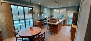 A modern kitchen with a large island, double ovens, and a dining area with a table and chairs.