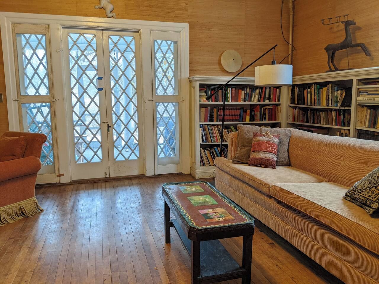 A cozy living room with a wooden floor, a sofa, a coffee table, and a bookshelf.