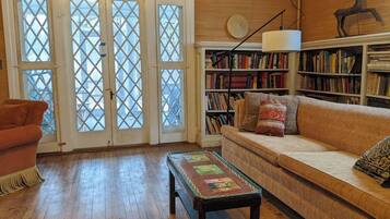 A cozy living room with a wooden floor, a sofa, a coffee table, and a bookshelf.
