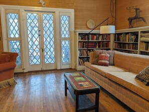 A cozy living room with a wooden floor, a sofa, a coffee table, and a bookshelf.