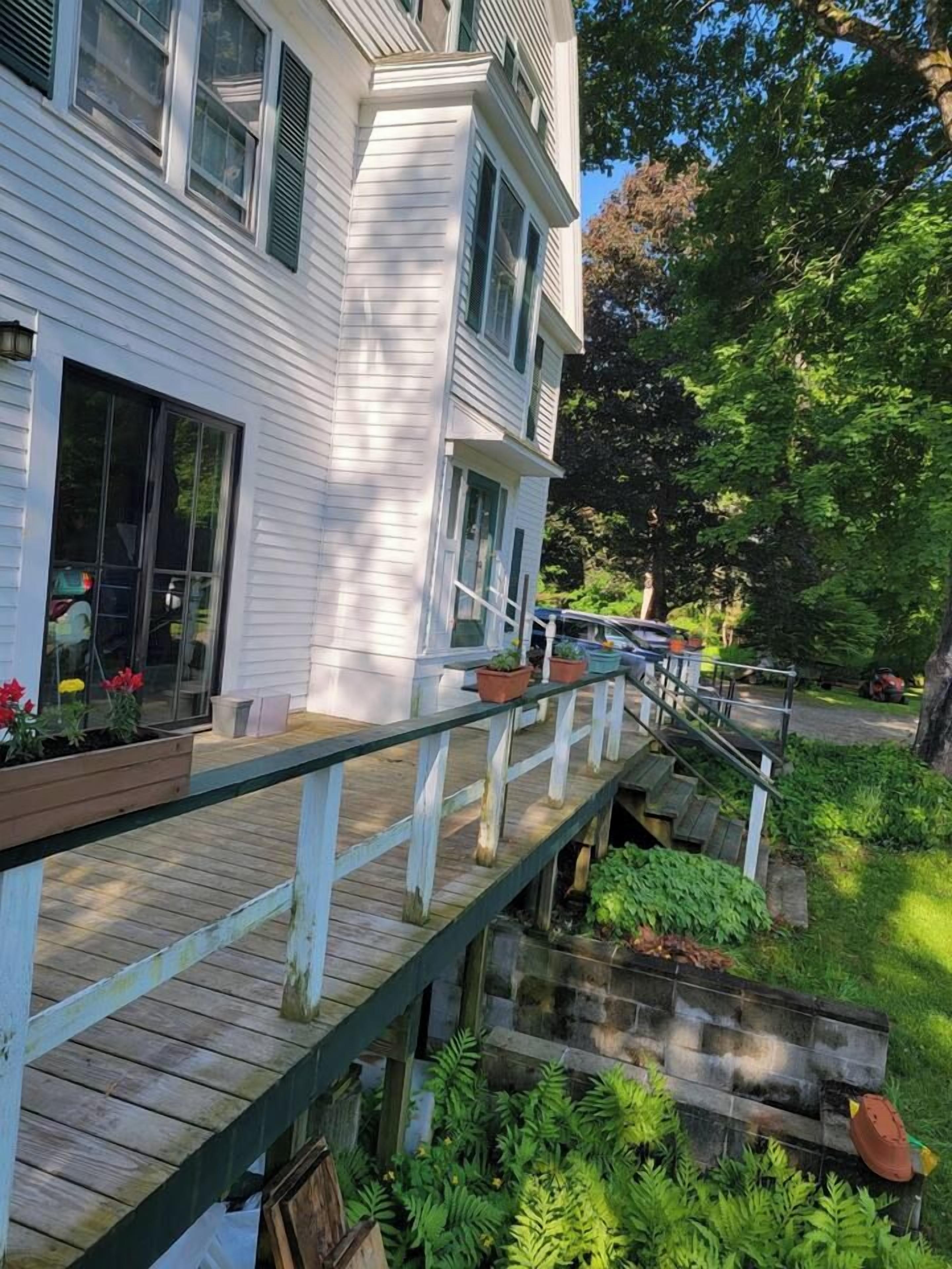 A two-story building with a covered outdoor deck and a small stream.