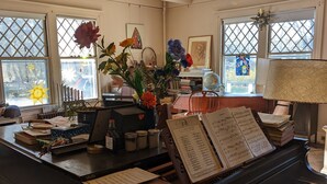 A piano room with a grand piano, music stands, and various decorative items. - Historic Stockbridge Villa on 25 acres (Stockbridge)