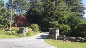 A rural road leading into a wooded area with stone pillars and a utility pole. - Historic Stockbridge Villa on 25 acres (Stockbridge)