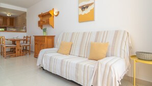 A cozy living area with a striped sofa, wooden dining table, and chairs. - VILLA VICTORIA - Charming house with shared pool. (Alaior)