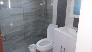 Ein Badezimmer mit Glasdusche, Toilette und Waschbecken mit Spiegel darüber.