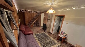 A cozy living room with a purple sofa, a patterned rug, a wooden staircase, and a ceiling fan. - Cozy retreat with canyon views, sound of the river, and the smell of the pines.  (Wallace)
