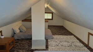 A small, cozy attic bedroom with a sloped ceiling, a single bed, a nightstand, and a window providing natural light. - Cozy retreat with canyon views, sound of the river, and the smell of the pines.  (Wallace)
