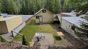 A small house with a green roof, a fenced yard, and a patio with a table and chairs. - Cozy retreat with canyon views, sound of the river, and the smell of the pines.  (Wallace)