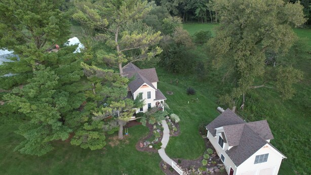 Vista aérea de una casa con un patio grande, rodeada de árboles y un pequeño estanque.