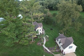 An aerial view of a house with a large yard, surrounded by trees and a small pond. - The Guest House (Boscobel)
