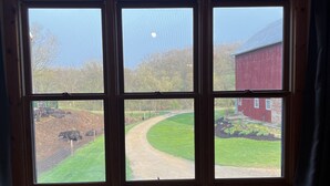 Una habitación con un ventanal grande con vistas a una granja.