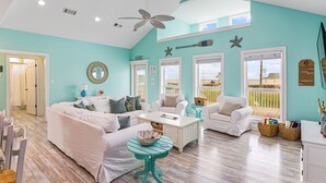 A spacious living room with white furniture, teal walls, and large windows. - Sweetheart savings! 3 min walk to Beach, Ocean View, WIFI, King 🛏 (Crystal Beach)