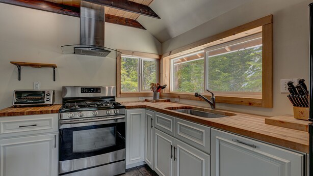 Una cocina moderna con armarios blancos, una estufa de acero inoxidable y un amplio ventanal con vistas al exterior.
